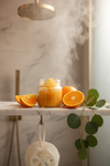 Citrus body scrub in a luxurious spa-like shower setting with fresh oranges